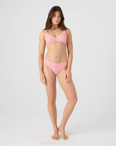 A woman stands barefoot against a plain white background, wearing the Roxy Crochet Hipster Full Bikini Bottom and looking at the camera with a relaxed expression, her arms by her sides.