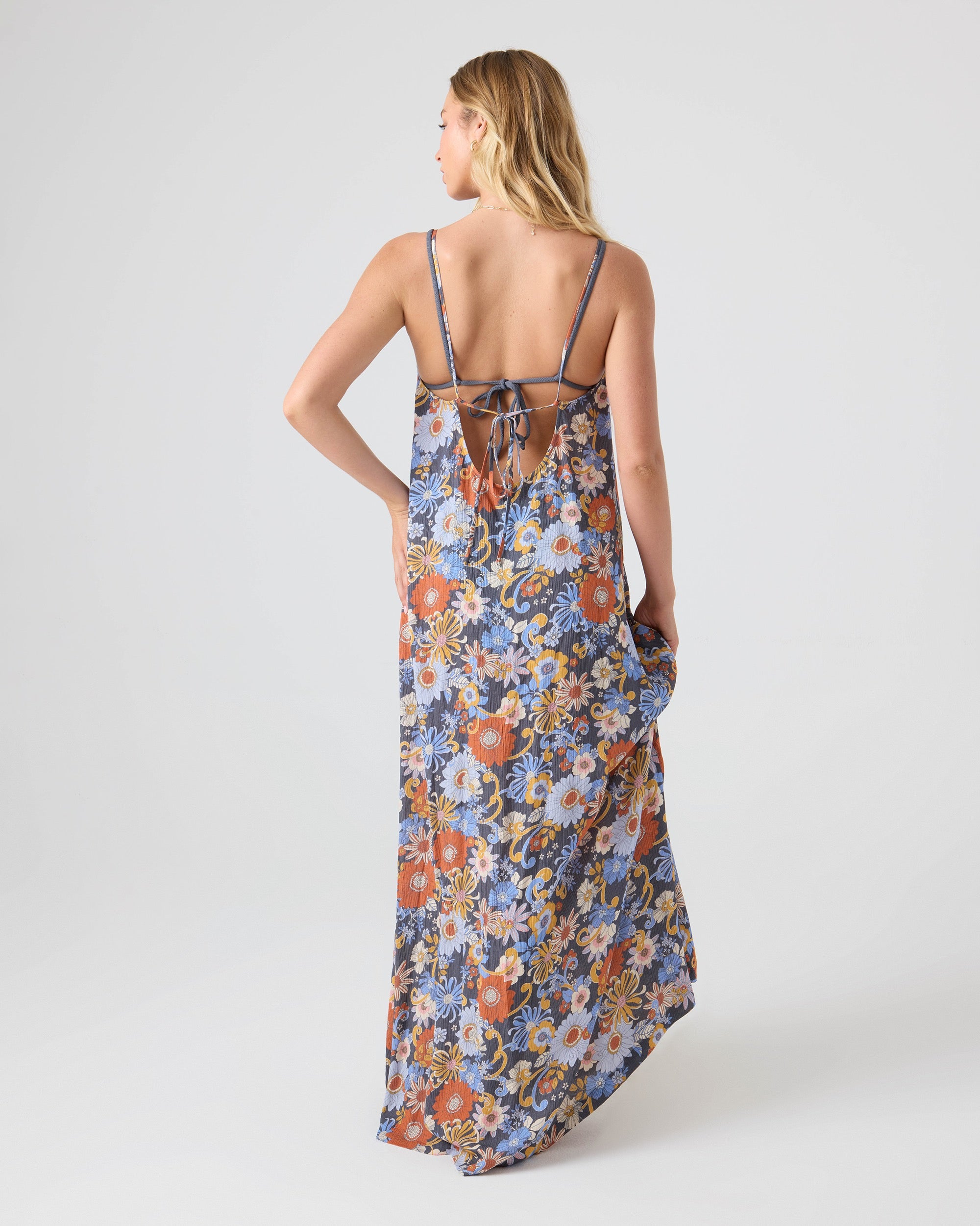 A woman faces away in the Roxy®一分钟极速赛车168开奖结果记录体彩历史号码查询 Soul Flower Cover Dress, a sleeveless tie-back maxi with an open back and thin center-tied straps. This chic floral beach cover-up features a colorful daisy and flower print.